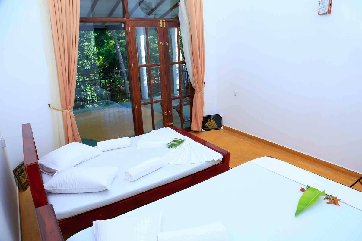 A room with a bed, a wooden headboard, and a view of greenery through a glass door.