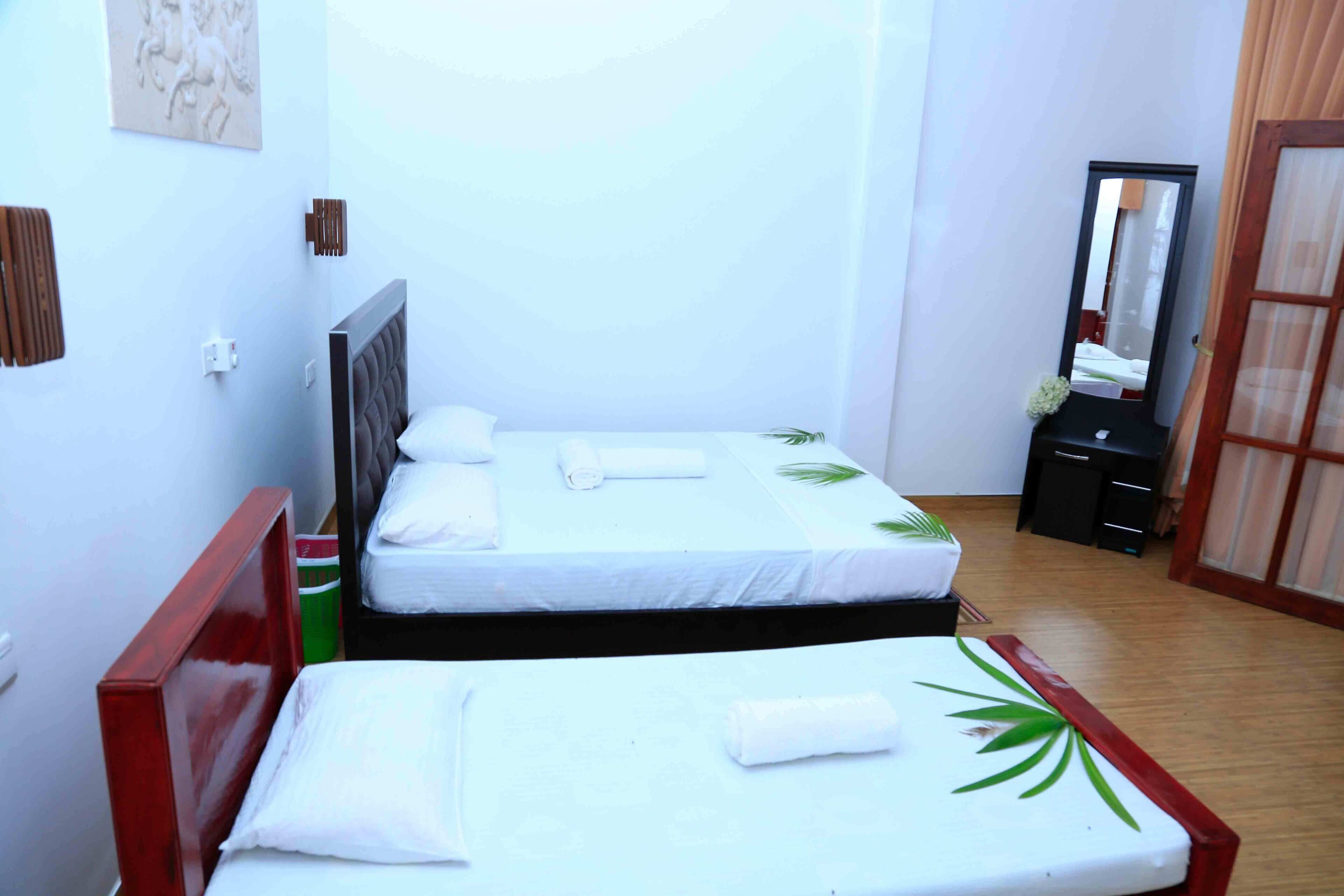 Habitación de hotel con dos camas, cabecero de madera, un espejo y una mesita con un florero.