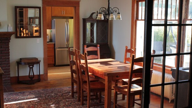 Un coin repas comprenant une table et des chaises en bois, un tapis, un meuble et un réfrigérateur.