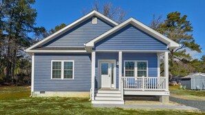 Une maison de plain-pied avec un porche à l’avant, un garage et un petit abri de jardin à l’arrière.