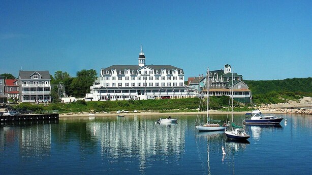 Ein Hotel am Wasserufer mit mehreren angestaubten Booten, ein großes Gebäude mit einem markanten Turm und ruhigem Gewässer.