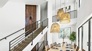 Un intérieur moderne avec un escalier, un coin repas et des œuvres d’art.
