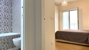 Une chambre avec un lit, une fenêtre et une salle de bain comprenant des toilettes et une douche.