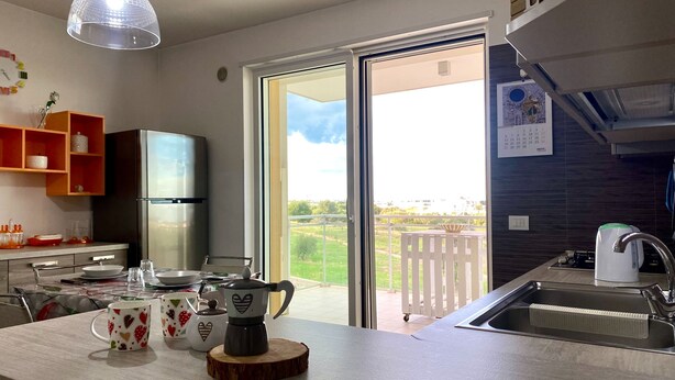 Une cuisine moderne dotée d’un grand îlot central, d’un réfrigérateur et donnant sur un balcon.