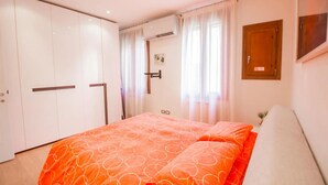 A bedroom with a bed, a wardrobe, and a window with curtains. - Ca’ Lunetta  (Venezia)
