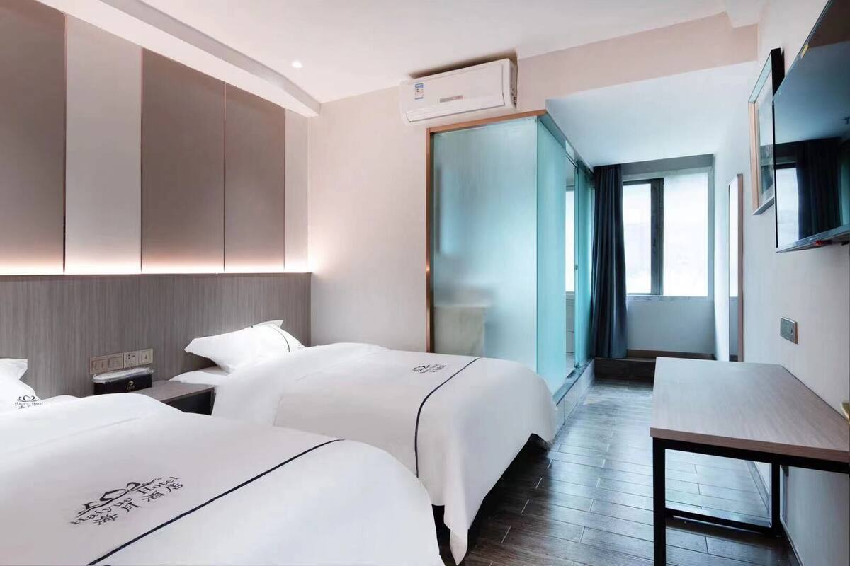 A hotel room with two beds, a desk, and a TV.