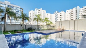 Ein Swimmingpool mit freiem Blick auf umliegende Gebäude und einer Rasenfläche.