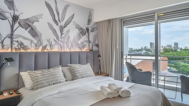 Ein modernes Hotelzimmer mit einem großen Bett, Blick auf die Stadt und einer Wandmalerei mit Pflanzen.