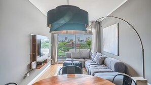Ein modernes Wohnzimmer mit einem Holzesstisch, einer Couch und einem großen Fenster mit Blick auf die Stadt.