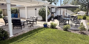 Un patio couvert aménagé avec du mobilier d’extérieur, un barbecue et un petit jardin.