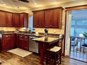 A kitchen with wooden cabinets, a granite countertop, and a built-in dishwasher.