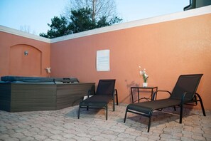 Un espace extérieur aménagé avec deux fauteuils et une petite table sur laquelle est posée une plante en pot.