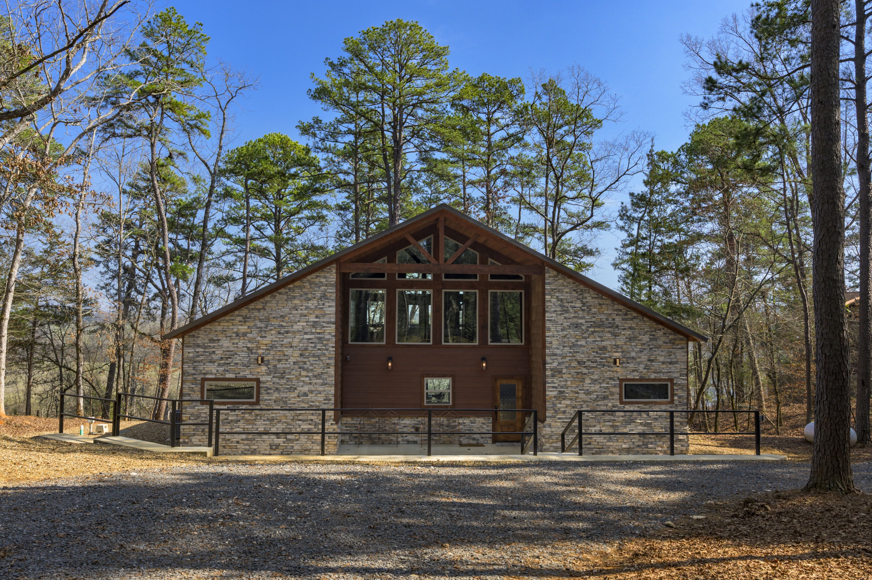 A stone building with a wooden roof, large windows, and a front door.