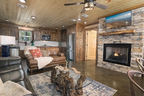 A spacious living area with a stone fireplace, leather sofa, and a glass coffee table.