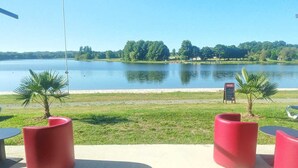 Eine Terrassensitzgelegenheit am Seeufer mit roten Sitzmöbeln und einem Coca-Cola-Schild.