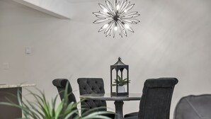 A dining area with a round table, four upholstered chairs, a decorative lantern, and a modern chandelier. - Bright and Cozy suite, great for work stays or vacations heart of Campbell River (Campbell River)