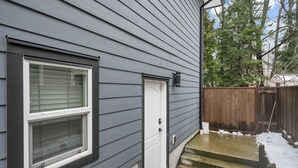 A house with a grey exterior, a white door, and a window with blinds. - Bright and Cozy suite, great for work stays or vacations heart of Campbell River (Campbell River)