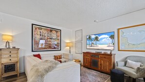 A living room with a sofa, a wooden cabinet, a television, and a map on the wall.