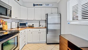 A modern kitchen with white cabinets, stainless steel appliances, and a wooden countertop. - Wilton Manors 2BR Charm! Walk to the Drive (Wilton Manors)
