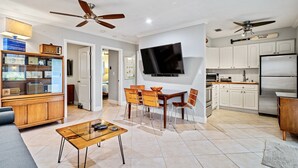 A modern living room with a flat-screen TV, wooden furniture, and a ceiling fan. - Wilton Manors 2BR Charm! Walk to the Drive (Wilton Manors)