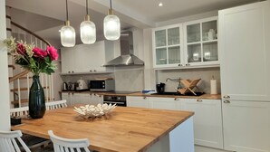 Een moderne keuken met witte kasten, een houten eettafel en een vaas bloemen.