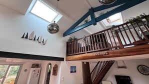 Un loft espacioso con techo alto, un balcón de madera y un tragaluz grande.