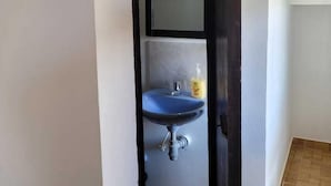 Une salle de bain avec un lavabo bleu, un miroir et un flacon de savon pour les mains.