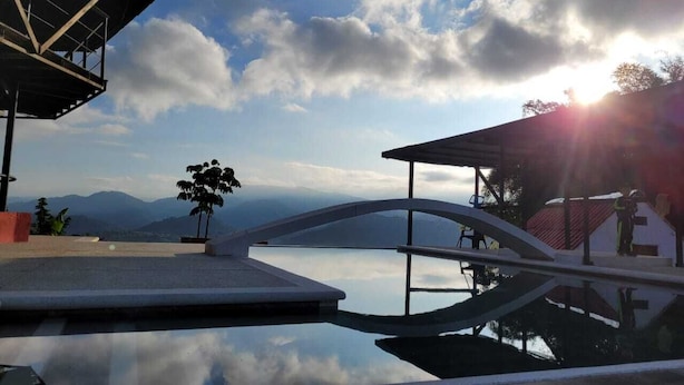 Une piscine à fond de verre, un pont et une vue sur les montagnes en arrière-plan.