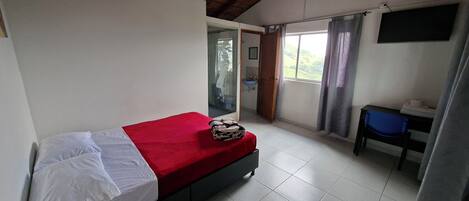 A room with a bed, a desk, a chair, a window with curtains, and a ceiling fan.
