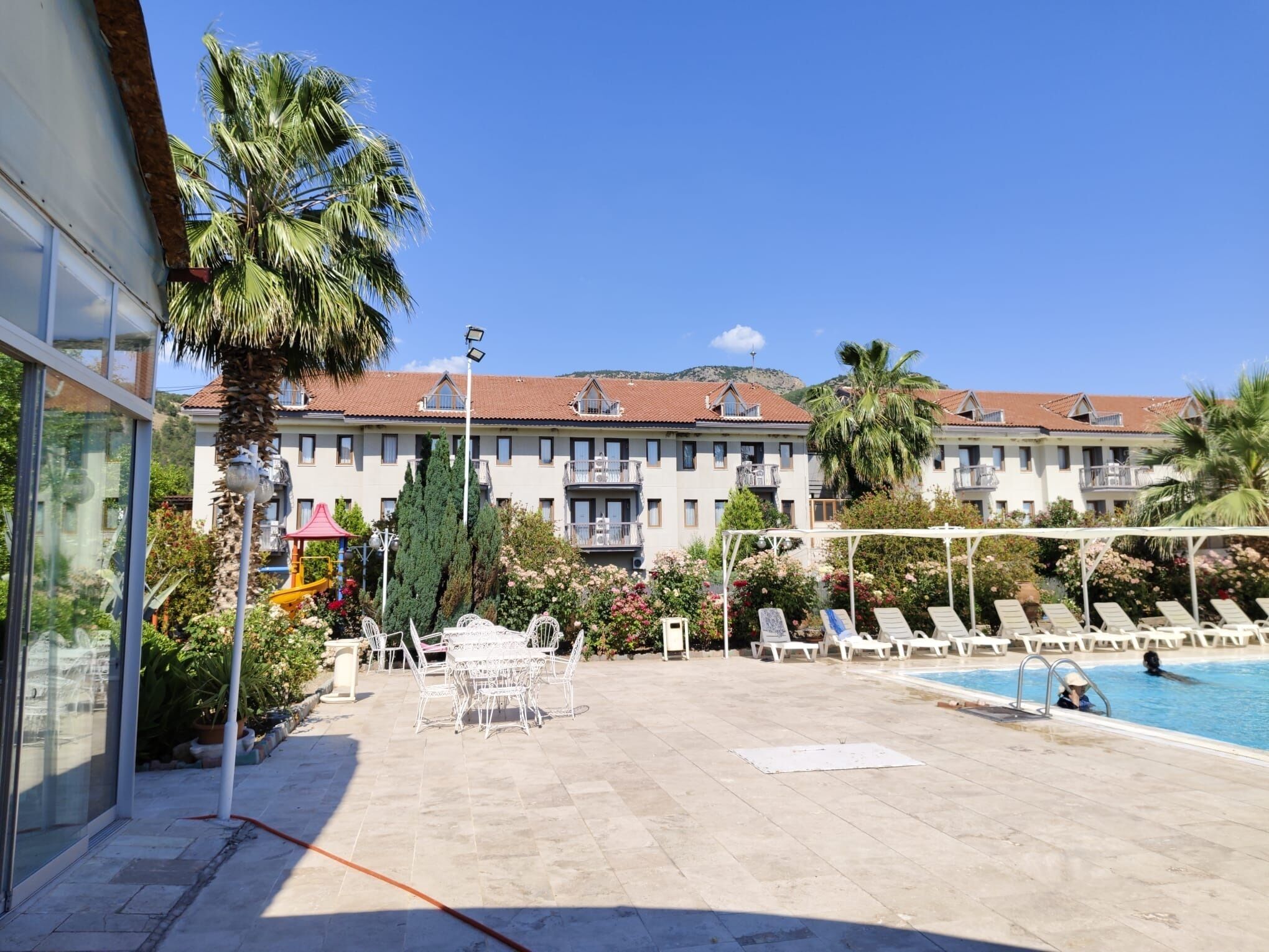 Un hotel con piscina, zona de estar al aire libre y vistas de los edificios circundantes.