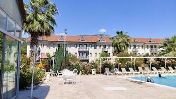 Un hotel con piscina, zona de estar al aire libre y vistas de los edificios circundantes.