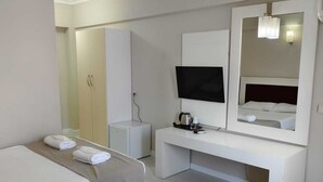 Habitación de hotel con dos camas, televisión, escritorio, espejo y armario.