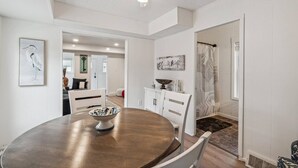 A dining area with a round table, white chairs, a bowl, and a ceiling fan.