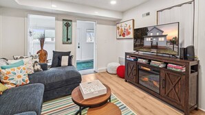 A modern living room with a grey sofa, a wooden coffee table, and a TV on a wooden cabinet.