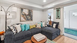 A modern living room with a sectional sofa, a coffee table, and a painting on the wall.