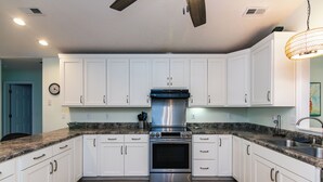 A kitchen with white cabinets, a stainless steel oven, granite countertops, and a ceiling fan. - The Ellis House:Pet Friendly Beach Home, 2 Screened Porches, Minutes to Beach Access (Edisto Beach)