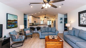 A spacious living area with a ceiling fan, a sofa, a coffee table, and a dining area with chairs. - The Ellis House:Pet Friendly Beach Home, 2 Screened Porches, Minutes to Beach Access (Edisto Beach)