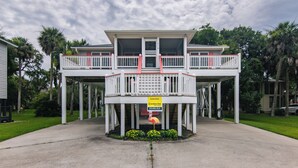 A two-story building with a balcony, a sign indicating it is a vacation rental, and a flamingo decoration. - The Ellis House:Pet Friendly Beach Home, 2 Screened Porches, Minutes to Beach Access (Edisto Beach)
