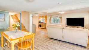Un amplio salón con una mesa de comedor de madera, un sofá y un televisor.