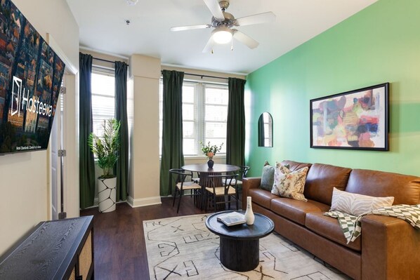 A living room with a brown leather sofa, a round coffee table, and a green wall.