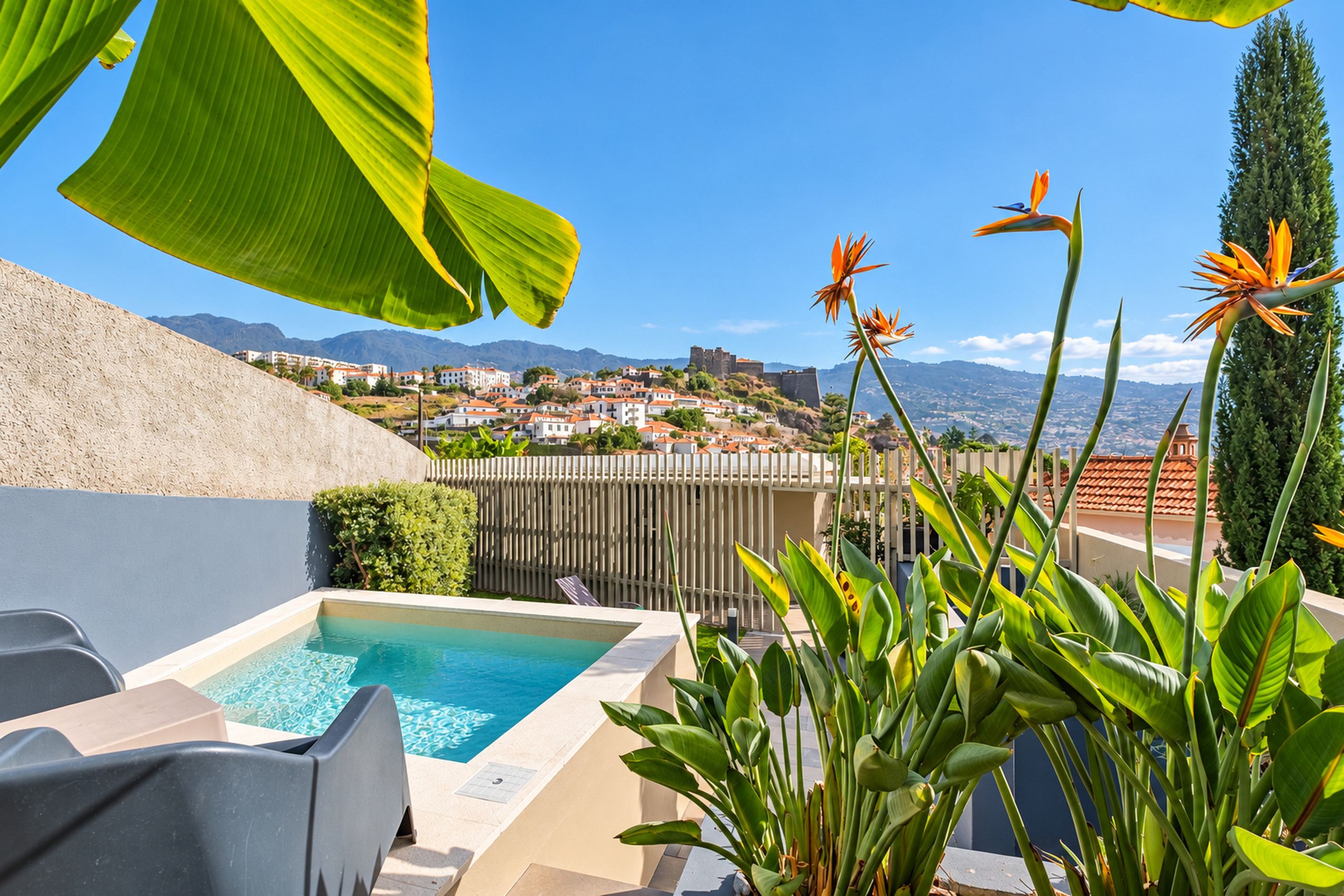 A rooftop pool with a view of a town and mountains in the background.