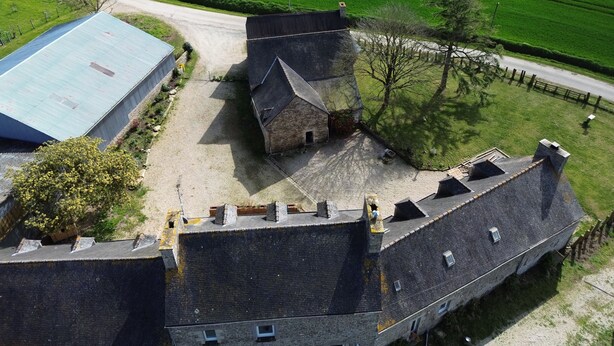Ein großes, historisches Steinhaus mit mehreren Schornsteinen und einem steilen Walmdach.