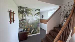Eine Treppe mit Holzbalken und Geländer, die zu einer Zwischenebene mit einem wandmontierten Spiegel und einem dekorativen Schrank führt.