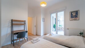 A bedroom with two beds, a desk, and a chair.