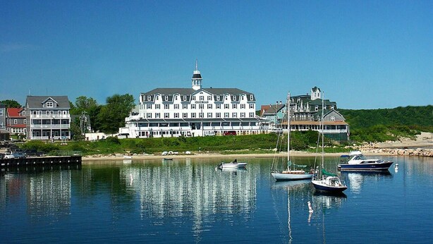 A large waterfront hotel with multiple stories, a prominent tower, and several boats docked in the water. - Old Bakery Inn (Block Island)