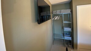 Un petit placard de rangement, doté d’étagères et d’une tringle pour suspendre les vêtements, d’une porte et d’un miroir.