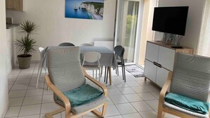 A modern living room with a dining area, a TV, and a large window with a view of cliffs. - Belle Maison Avec Jardin et Parking Privée (Honfleur)