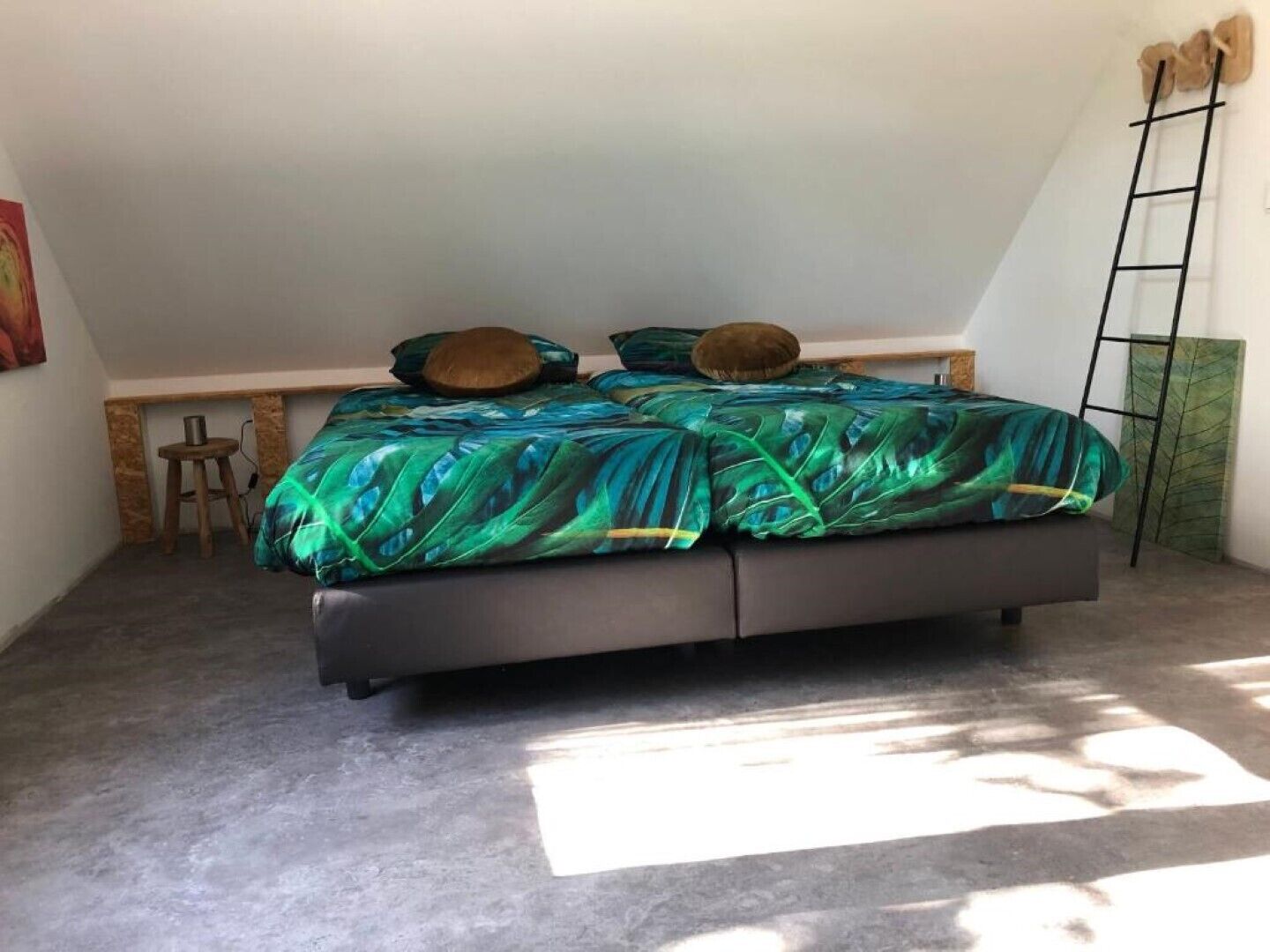 A bedroom with a bed, a wooden bench, and a ladder against the wall.