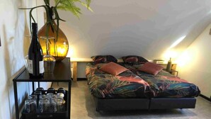 Une chambre à coucher avec un lit, une table de chevet, une étagère avec des verres et une plante.