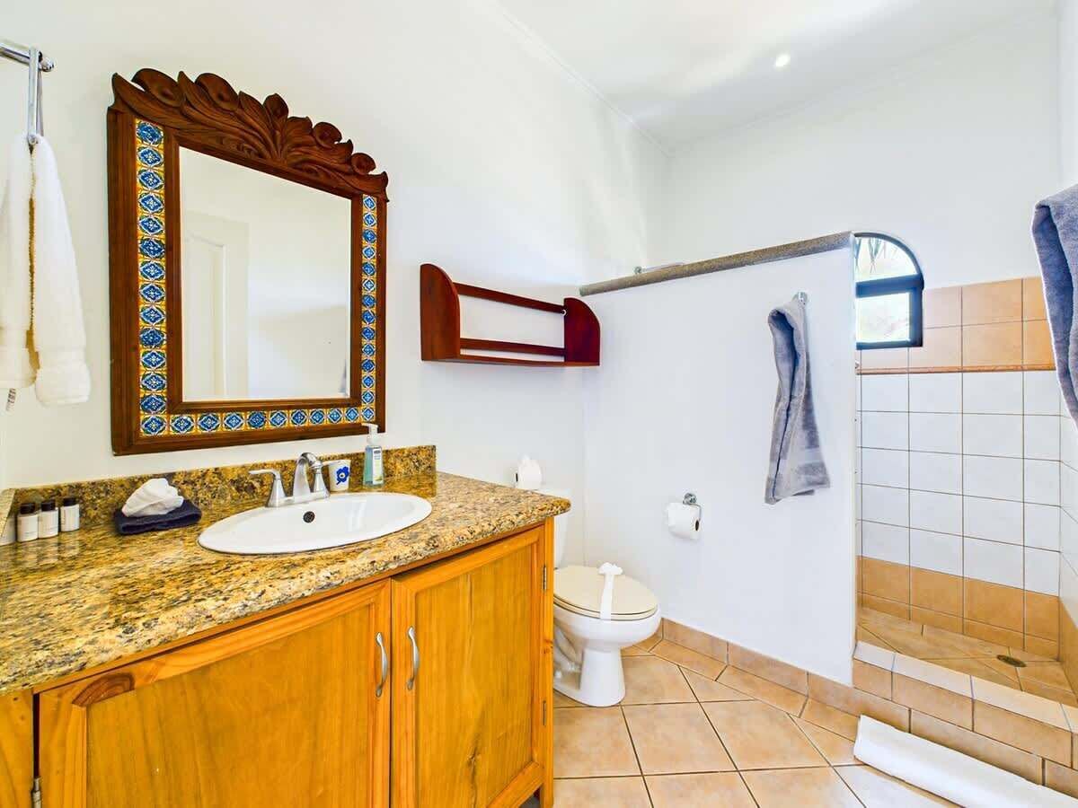 Une salle de bain avec un meuble-lavabo en bois, un évier, des toilettes et un espace douche.